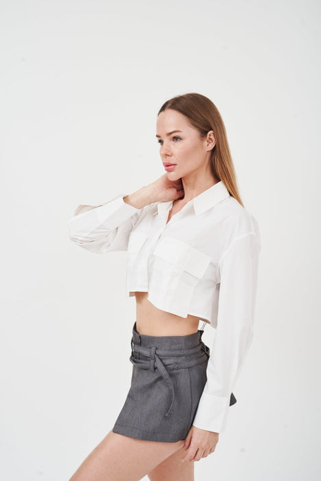 Stylish ruffle-trim white blouse with flared sleeves, modeled in studio setting.