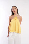 Elegant floral embroidered halter top in vibrant yellow, featuring a stylish rose detail at the neckline, worn by a female model with long dark hair against a plain white background.