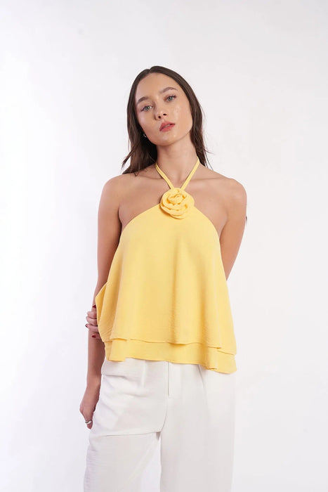 Elegant floral embroidered halter top in vibrant yellow, featuring a stylish rose detail at the neckline, worn by a female model with long dark hair against a plain white background.