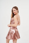 Elegant shimmering champagne slip dress showcased on a smiling woman with long brown hair against a plain white background.